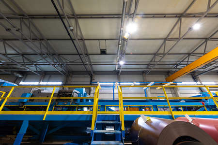 Production line of metal tile for roof. Steel forming machine in metalwork factory workshop. Metal sheet profiling machineの写真素材