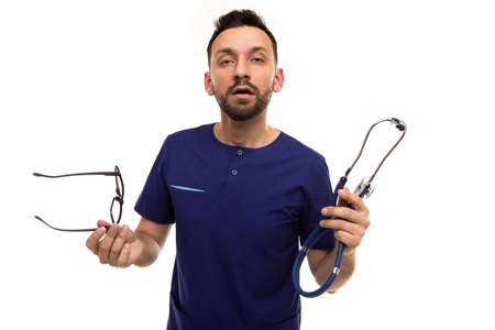 serious doctor questioning looking at the camera holding glasses and a stethoscopeの写真素材