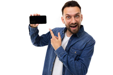 handsome young man points finger at smartphone screen with with charismatic emotions on face on...
