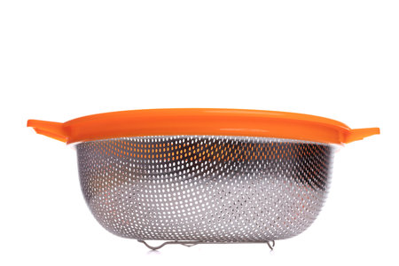 Empty metal colander on legs with orange rim on white backgroundの写真素材