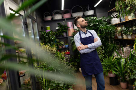 male florist in blue aprons in a shop of flowers and bouquets.の写真素材