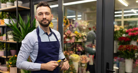 attractive male florist next to refrigerator with fresh fresh flowersの写真素材