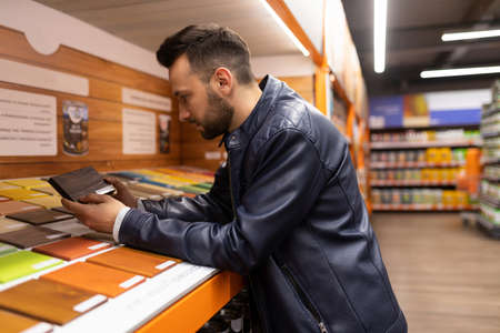 a man in a hardware store next to a palette of terrace oil and wood varnish.