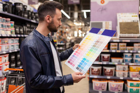 a man in a hardware store with a palette of paints for wall decoration in his hands concept of...