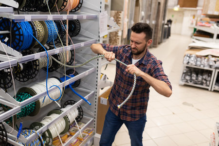 a customer in a hardware store checks the strength of a safety rope for climbing and high-altitude workの写真素材
