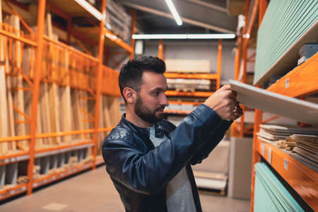 buyers a man in a hardware store chooses drywall for the construction of a new houseの写真素材