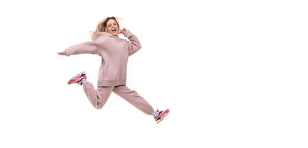 young woman in a jump in a tracksuit of beige color on a white isolated backgroundの写真素材