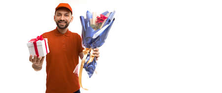 delivery courier with a bouquet of flowers and a gift in a red uniform on a white background with copy-spaceの写真素材