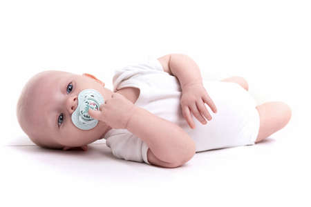 adorable baby with a pacifier in his mouth lies on his back on a white background