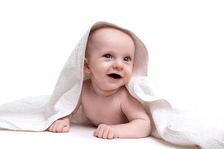 charming baby on a white background under a towel looking at the camera with a smile