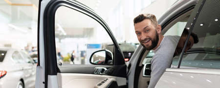 satisfied customer peeks out from behind the wheel of a new SUV at a car dealership