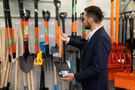 a man chooses a new shovel and another tool for gardening