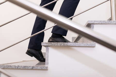 a businessman moves up the steps to the top, close-up of the steps and male legsの写真素材