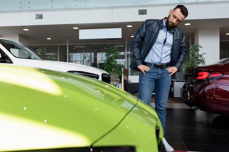 a man in a car dealership chooses a sports car for himselfの写真素材