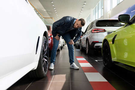 a man in a car dealership chooses new tires and alloy wheels for his car