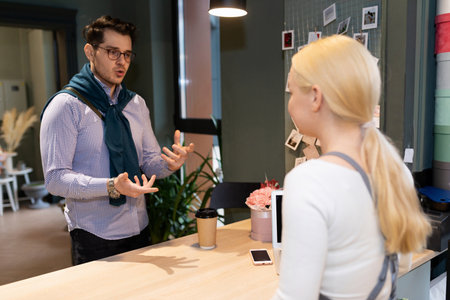 a customer in a flower shop explains to the florist what kind of bouquet he wants to buy for a loved...