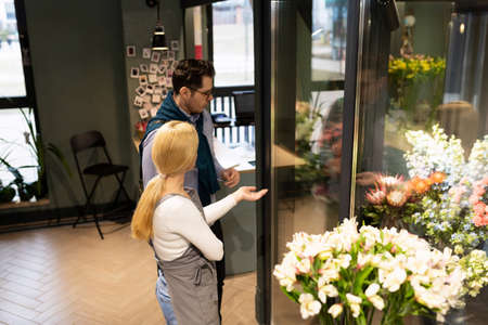 the seller and the buyer in the flower shop are determined with a set of flowers for the bouquetの写真素材