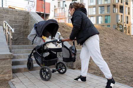 a young mother tries with a baby stroller to drive up the stairs