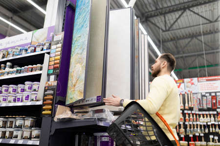 a buyer in a construction hypermarket compares prices for finishing materials