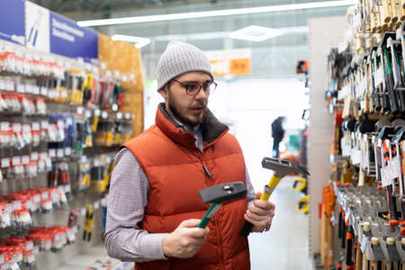 a man chooses a new hammer in a construction hypermarketの写真素材