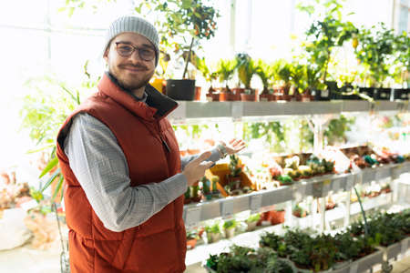 happy customer in hardware store next to shelves with potted plantsの写真素材