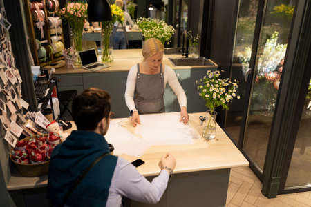 florist in a store of fresh flowers and bouquets at work next to a client