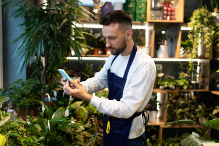 the manager of the flower salon takes pictures of the ordered bouquet on a mobile phone