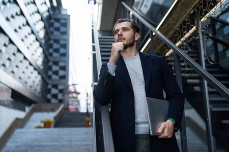 pensive male head on the background of the city business center with a laptop in his hands, Concept business planningの写真素材