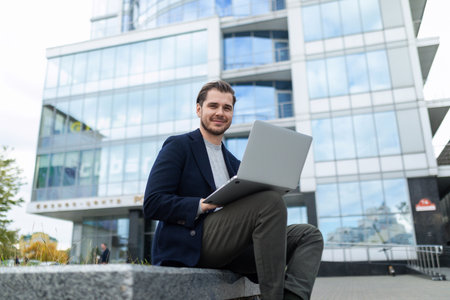 successful businessman works remotely online outdoors outdoors against the backdrop of a city buildingの写真素材