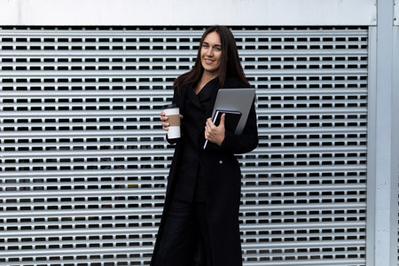 portrait of a successful business woman with a laptop and a cup of coffee against the background of...