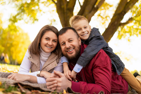 close-up portrait of a happy traditional family with a small child in a park on the groundの写真素材