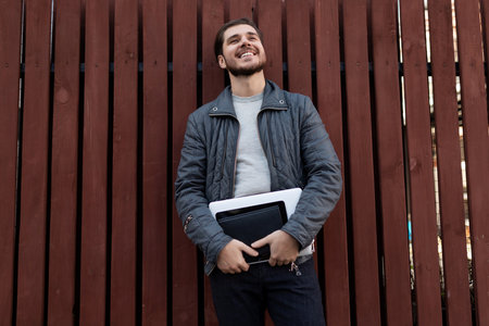 happy man Businessman with a laptop in his hands looks dreamily up on the background of wooden...