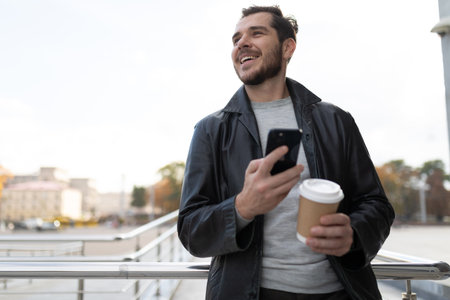 a man with a mobile phone in the city drinking coffeeの写真素材