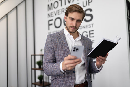 business man with a phone diary in his hands makes notes in the officeの写真素材