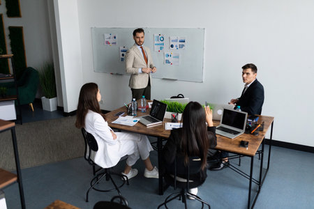 a group of entrepreneurs of different nationalities at a table in the office solve a business...