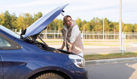 mature woman at the open hood of a broken car