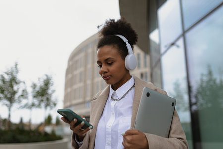 young african woman freelancer listening with headphones and walking in city street
