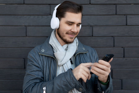 european male freelancer listening to music on headphones in app on phoneの写真素材
