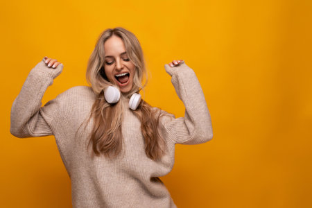 cute lady with headphones around her neck smiling on a yellow backgroundの写真素材