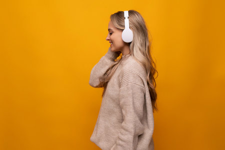 girl attentively listens to a podcast in headphones on a yellow backgroundの写真素材
