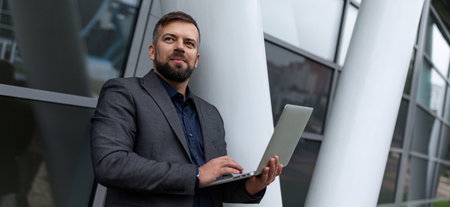 pensive male architect with a laptop works on the background of the buildingの写真素材