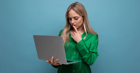 thoughtful business lady freelancer working with a laptop in her hands on a blue bright backgroundの写真素材