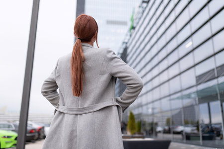 young woman designer with a ponytail hairstyle against the background of a large glass buildingの写真素材