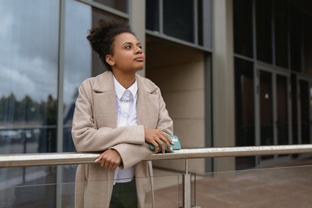 American young woman designer stands thoughtfully in front of a glass business centerの写真素材