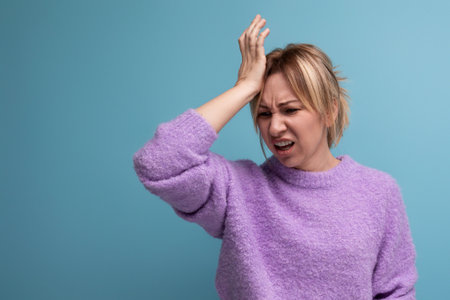 distressed upset blond young woman in purple hoodie on blue background with copy spaceの写真素材