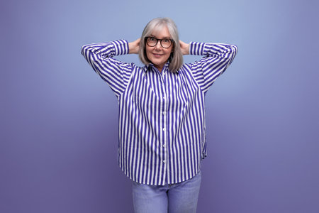 kind fashionable 50s middle aged woman with gray hair in a trendy outfit on a bright studio background with copyspaceの写真素材