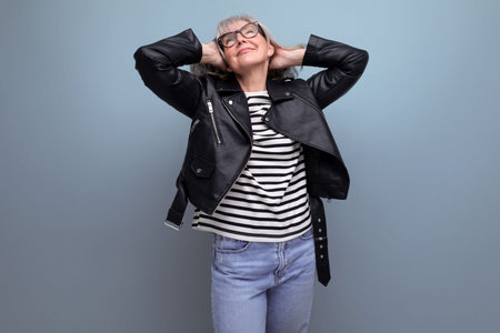 adorable gray-haired 60s mature woman in a stylish jacket on a bright backgroundの写真素材