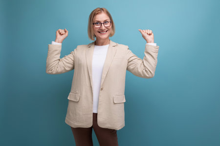surprised adult woman with a bob hairstyle in a classic jacket points to the side on a bright background with copy spaceの写真素材
