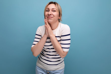 cute blond young woman in a striped sweater on a blue background with copy space