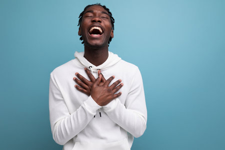 joyful winner african 20s man with dreadlocks on background with copy space